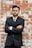 A man in a business suit standing confidently with arms crossed.