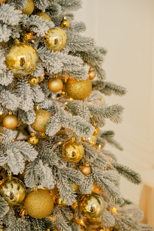 A beautifully decorated Christmas tree with warm white lights and red ornaments in a cozy living room setting.