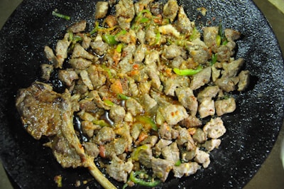 Grilled chapli kababs sizzling on a traditional flat pan, garnished with fresh herbs.