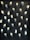 A wall is covered with multiple surveillance cameras arranged in a grid pattern. The cameras are uniform in shape and color, creating a stark and somewhat ominous appearance against the dark background.