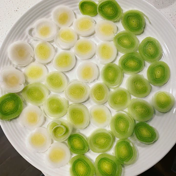 Close-up of a dish garnished with sliced leeks and herbs.