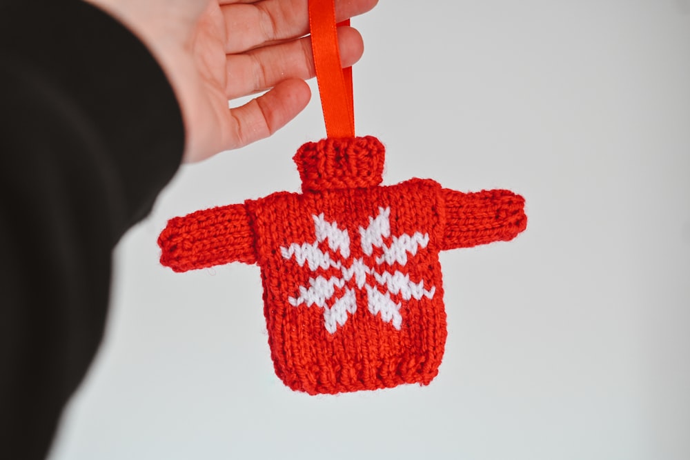 a hand holding a red and white knitted scarf