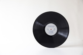A vinyl record with a visible label at the center sits against a minimal white background.
