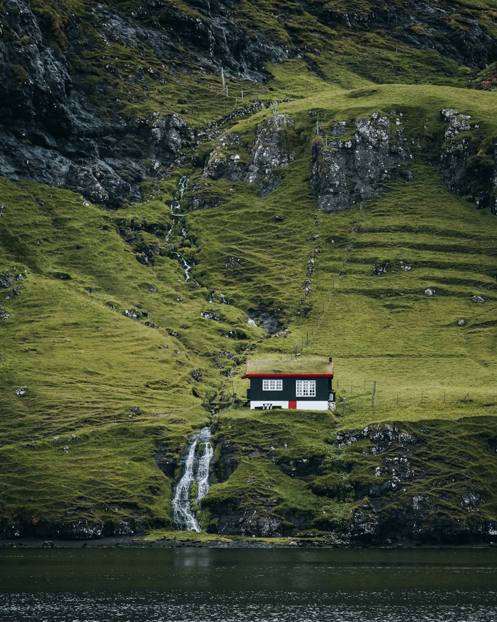 a house on a cliff by a waterfall