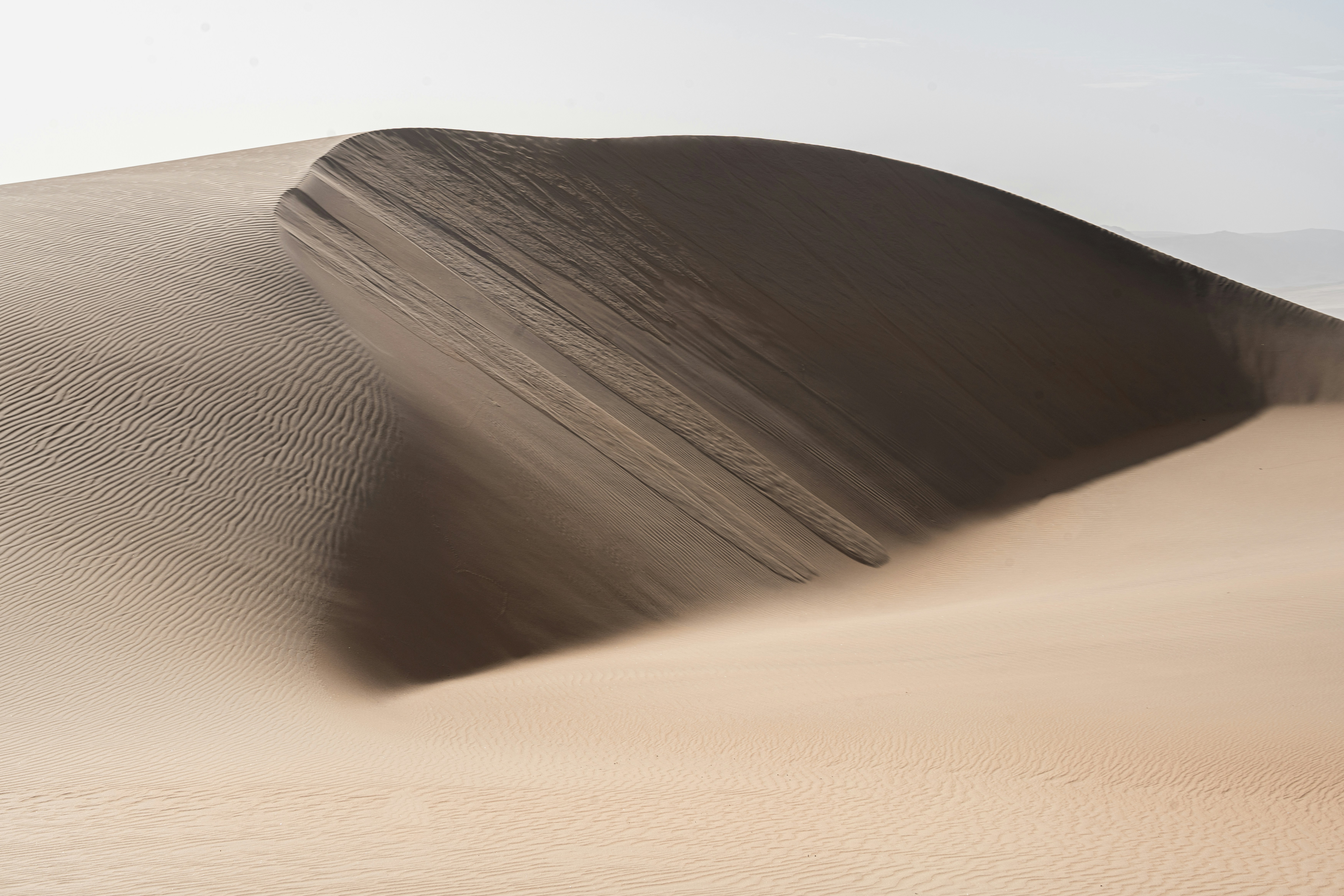 a sand dune with a few people on it