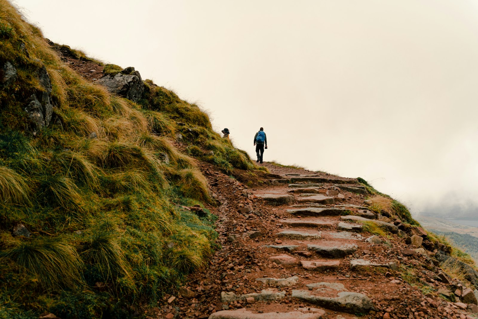A person walking a path in foggy, misty British hills