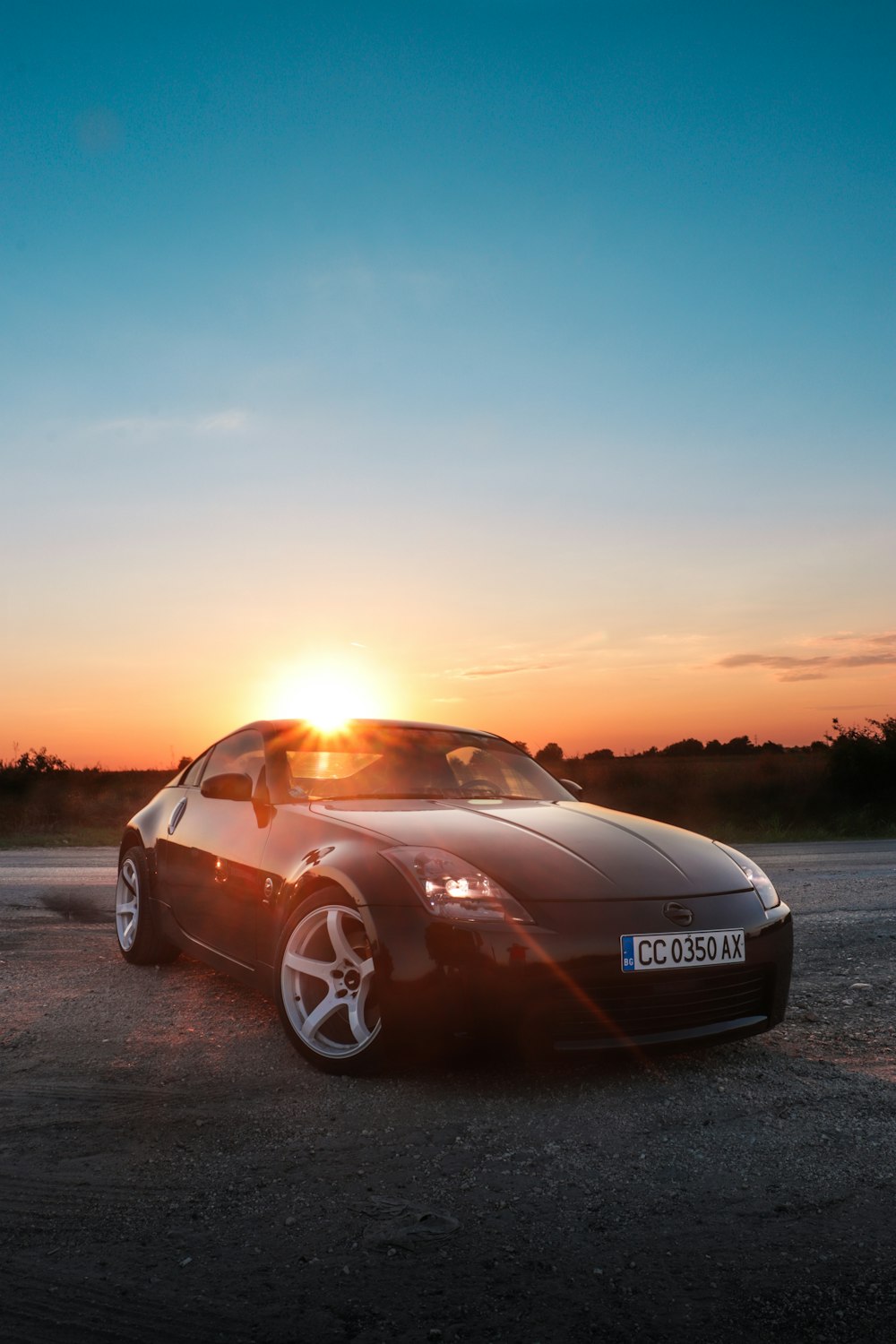 a car parked on a road with the sun setting behind it