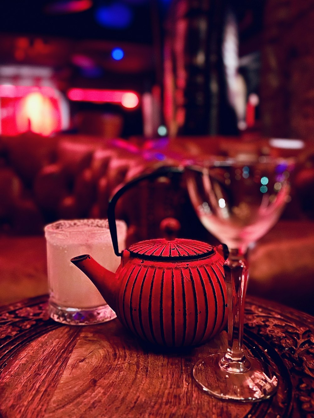 a glass of wine next to a teapot and a tea kettle