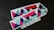 A stack of rectangular stickers featuring a geometric design with vibrant colors. The design includes overlapping triangles and other shapes with a glittery texture. The word 'DESIGN' is printed in a bold font at the bottom.
