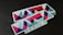 A stack of rectangular stickers featuring a geometric design with vibrant colors. The design includes overlapping triangles and other shapes with a glittery texture. The word 'DESIGN' is printed in a bold font at the bottom.