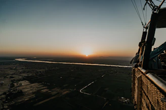 Passengers enjoying a peaceful hot air balloon ride with panoramic views of lush green valleys.