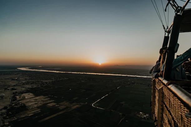 Passengers enjoying a peaceful hot air balloon ride with panoramic views of lush green valleys.