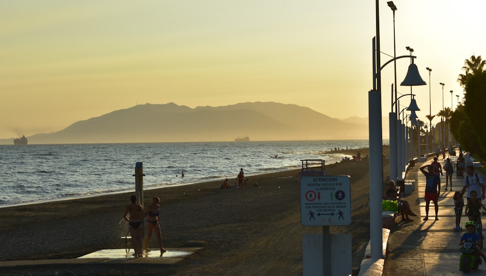 people walking on a sidewalk near a beach