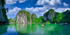 a body of water with trees and rocks in it with Ha Long Bay in the background