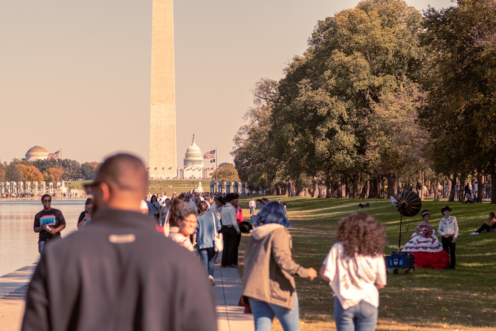 a group of people walking on a path with a monument in the background