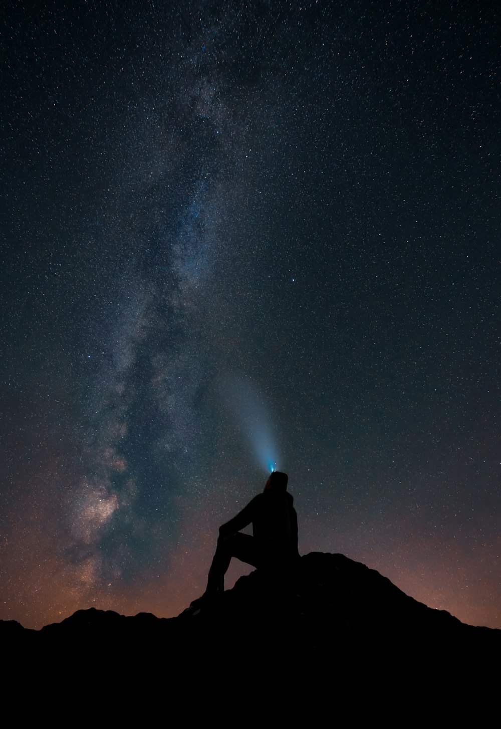 a person sitting on a mountain looking at the stars in the sky