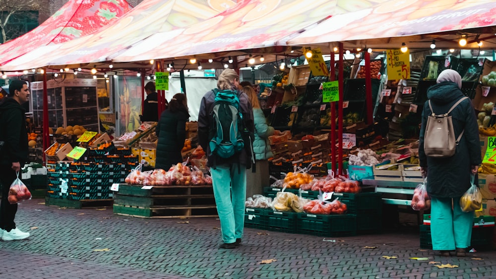 Personas de pie frente a un puesto de frutas