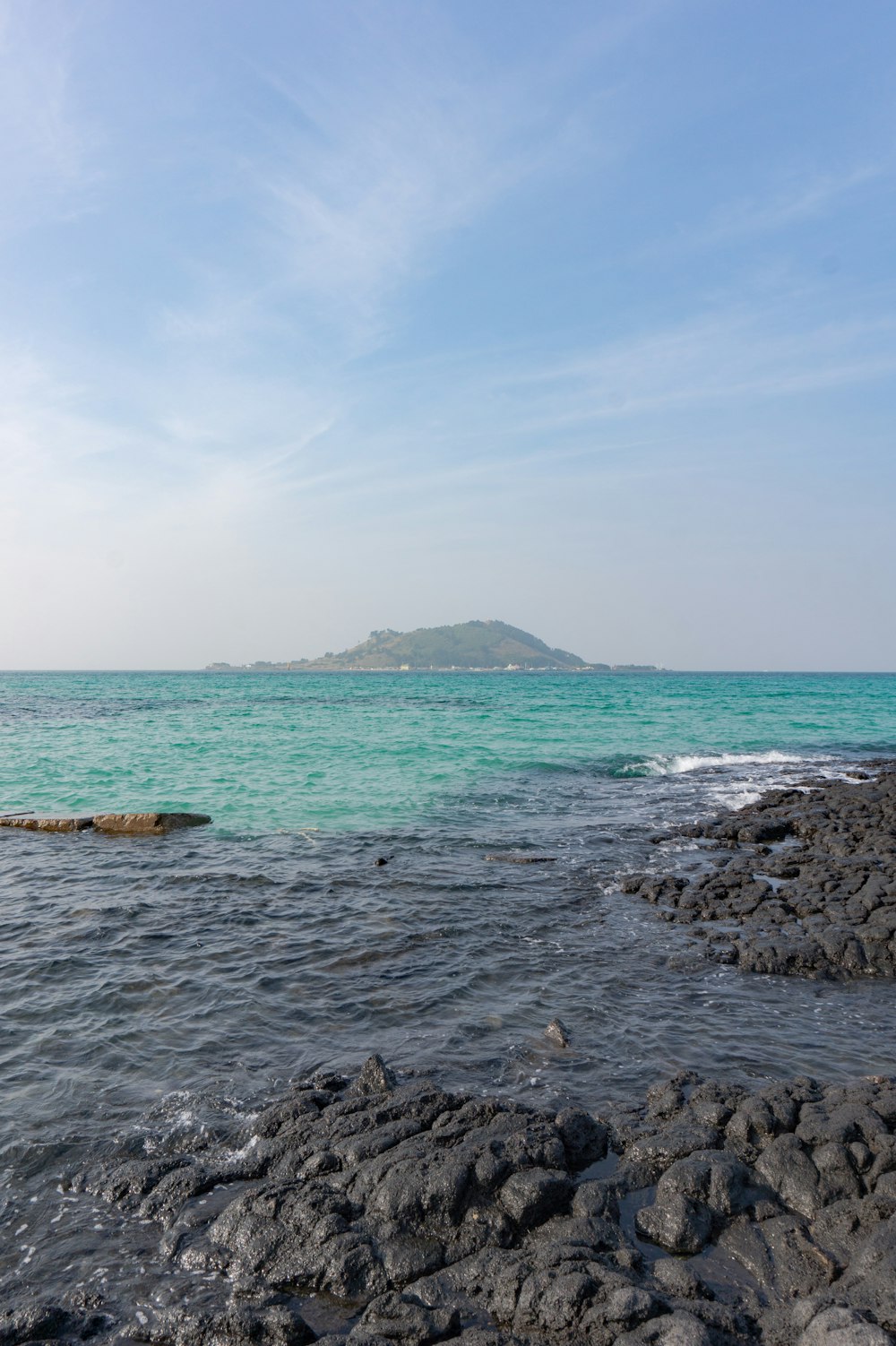 a rocky beach with a large island in the distance