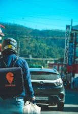 A delivery rider on a scooter carrying a branded The Burger Cafe bag through Pune streets.