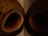 Two dried coconut shells lie on a surface with open hollow centers pointed outward. The lighting is dim, casting deep shadows within the shells and highlighting the textured surface and natural brown color of the coconut husks.