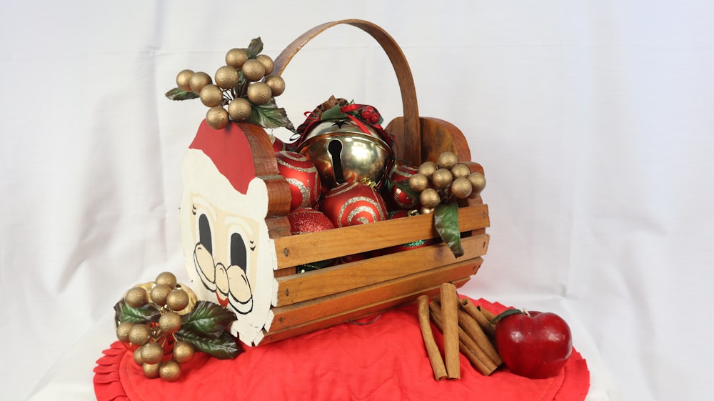 a wooden teapot with a tea set and fruit on a red tablecloth