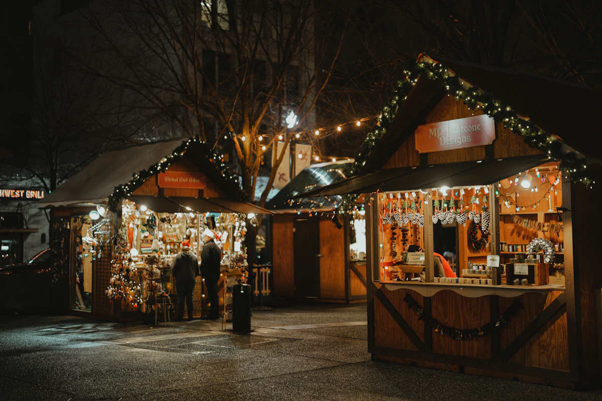 Wooden market huts lit against the dark with snow on the ground