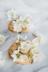 Delicate butter cookies shaped like flowers on a lace doily.