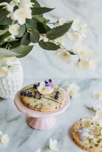 Close-up of elegantly iced wedding sugar cookies arranged with soft blush florals.