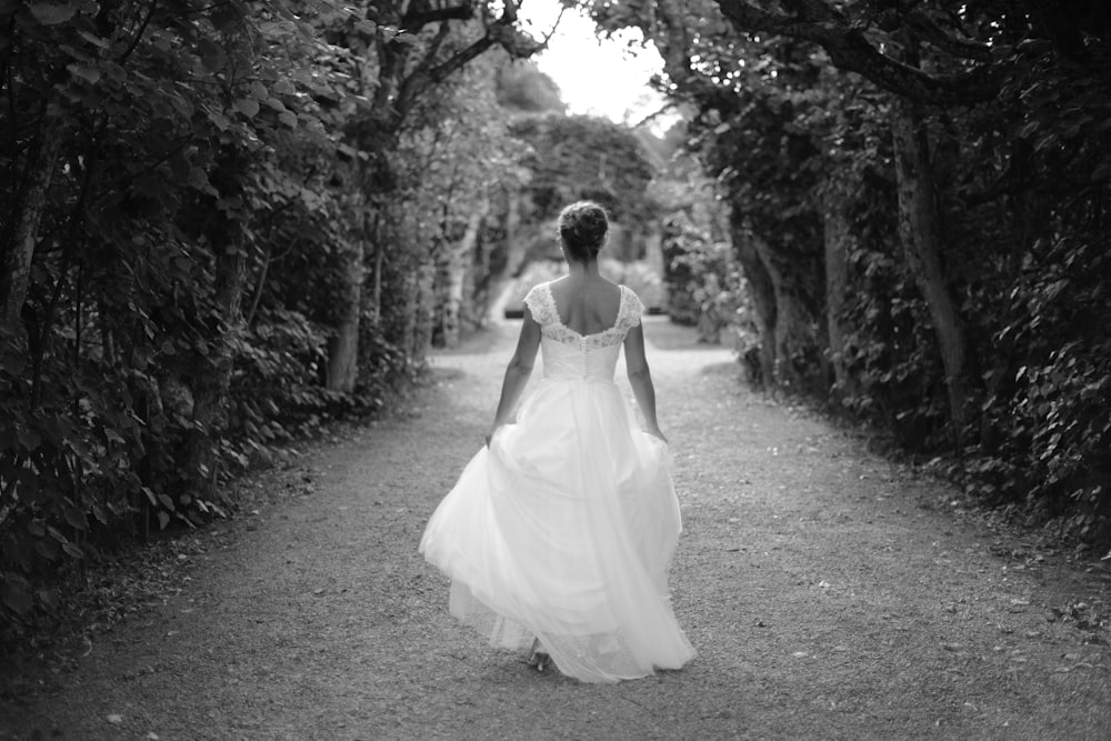 a person in a white dress walking down a path in the woods