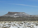 A sunlit mesa rising sharply against a clear blue sky.