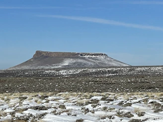 A panoramic view from the top of a flat-topped mesa with distant mountains