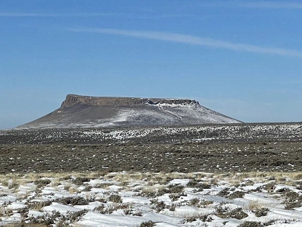 A panoramic view from the top of a flat-topped mesa with distant mountains
