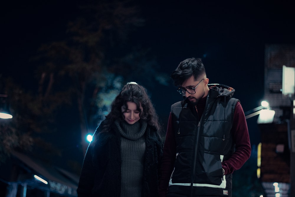 a man and woman standing next to each other at night