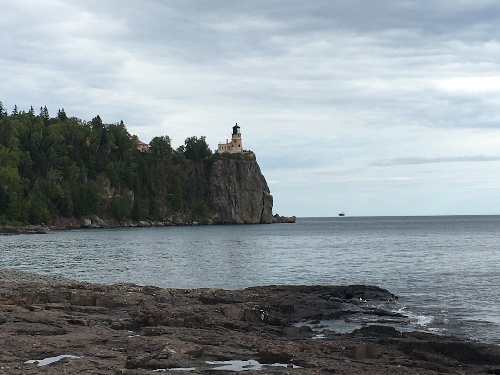 a rocky cliff with a lighthouse on it by the water