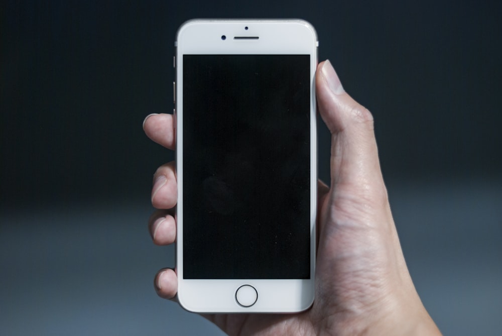 a hand holding a white cell phone