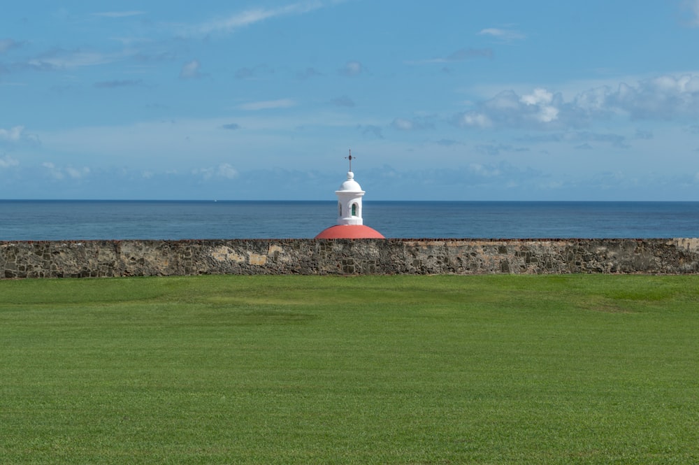 a white lighthouse on a grassy hill