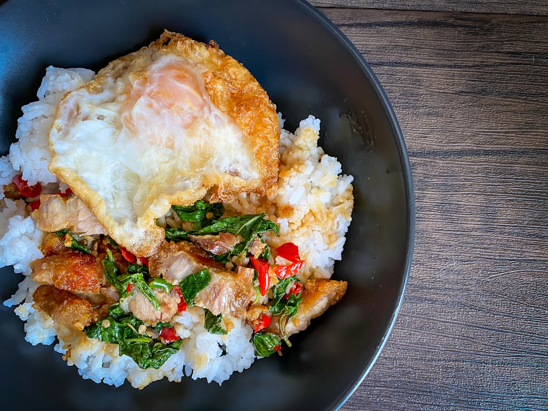 Rice topped with stir-fried pork and basil with a fried egg on the table