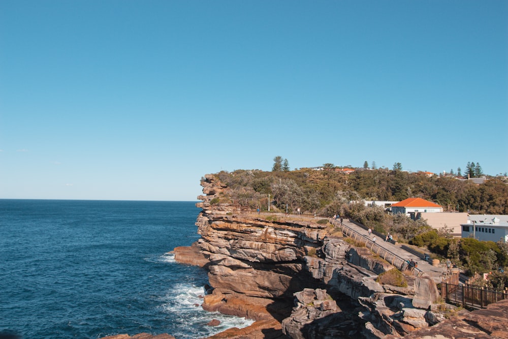 a rocky beach with buildings and trees