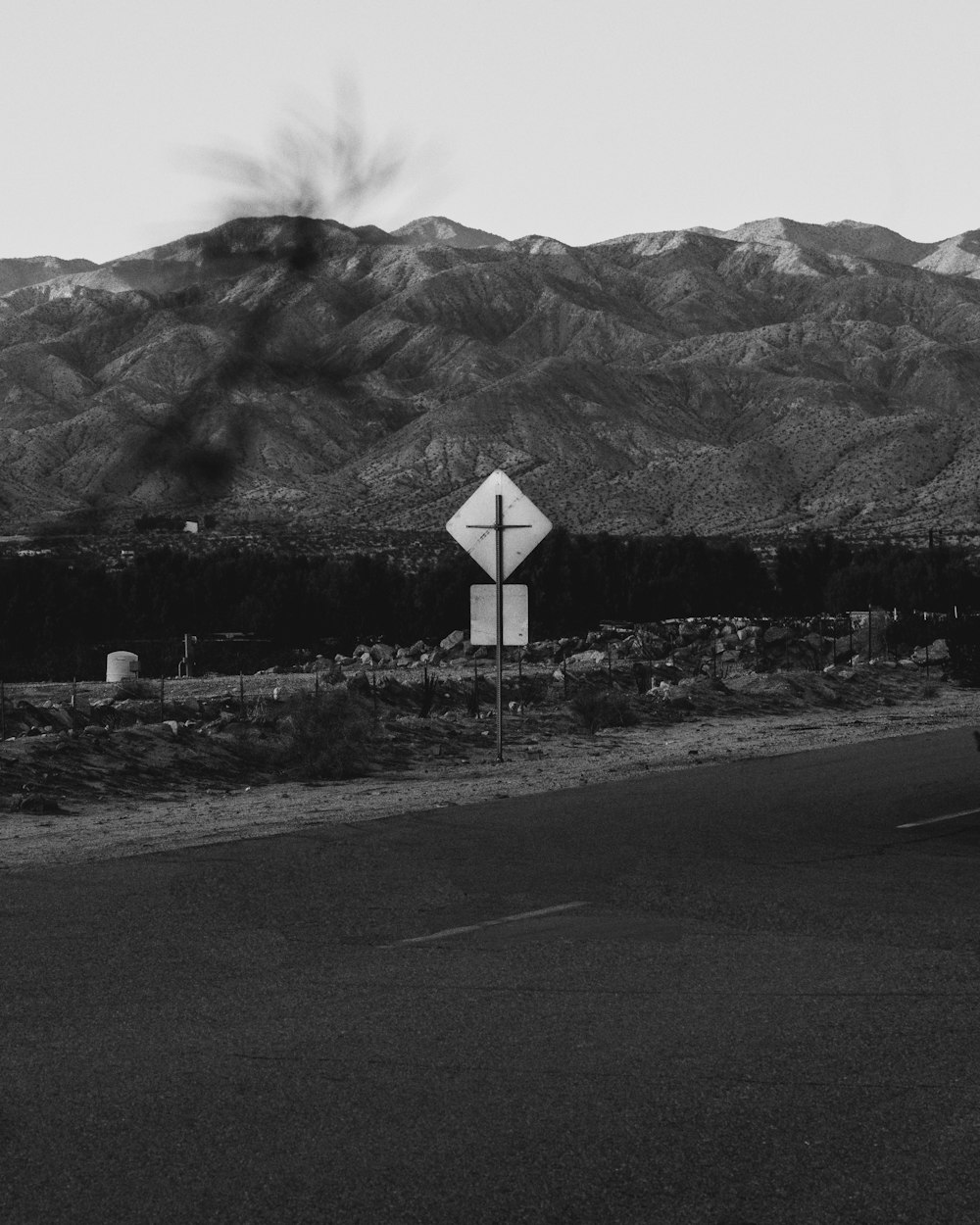 a road with a sign on it and mountains in the background