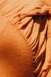 Close-up of orange-red tent fabric with detailed stitching and waterproof texture.