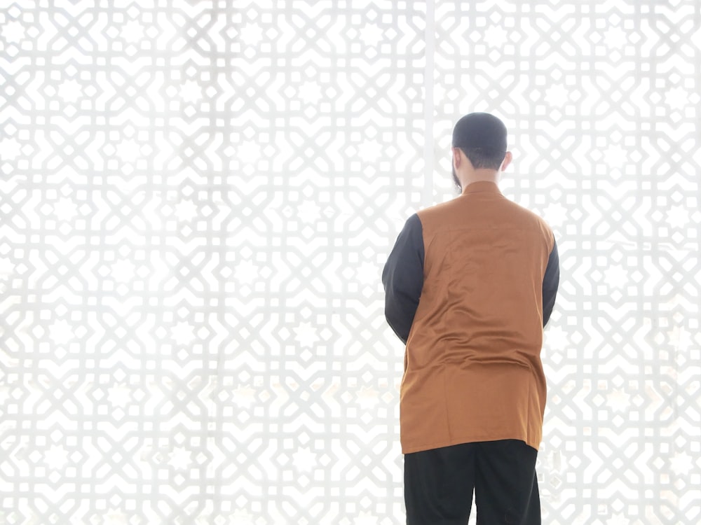 back view of a man standing in front of a wall with a grid of dots