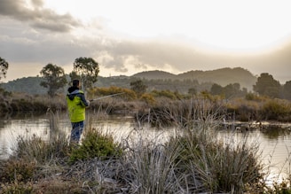 A serene fishing spot at dawn with members in military green jackets by the water.
