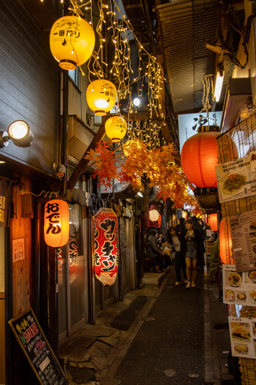 A narrow Japanese alley illuminated by warm lanterns at night