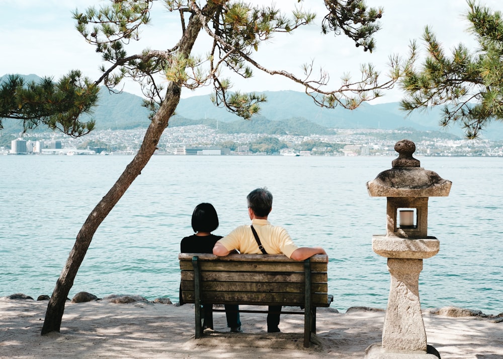 a person and a child sitting on a bench by a lake