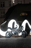 A sleek black motorcycle parked against a bright Singapore cityscape at dusk