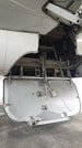 The image depicts the open undercarriage panel of an aircraft, with visible mechanical components and interior structure. The panel shows signs of wear and exposure to dirt, suggesting usage. The background includes parts of the aircraft's wing and various hydraulic and structural elements.