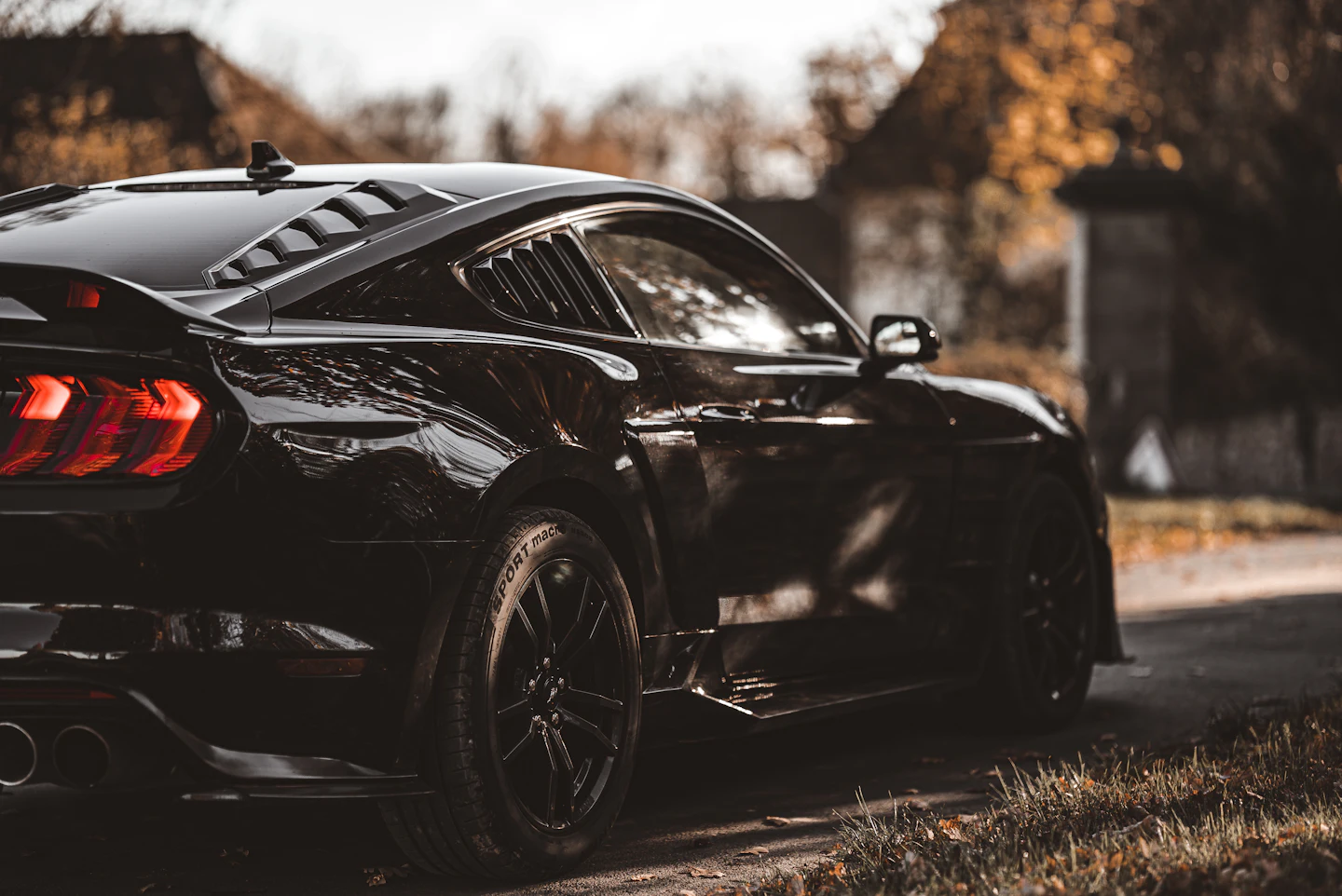 Black sports car with dark tinted windows parked at dusk