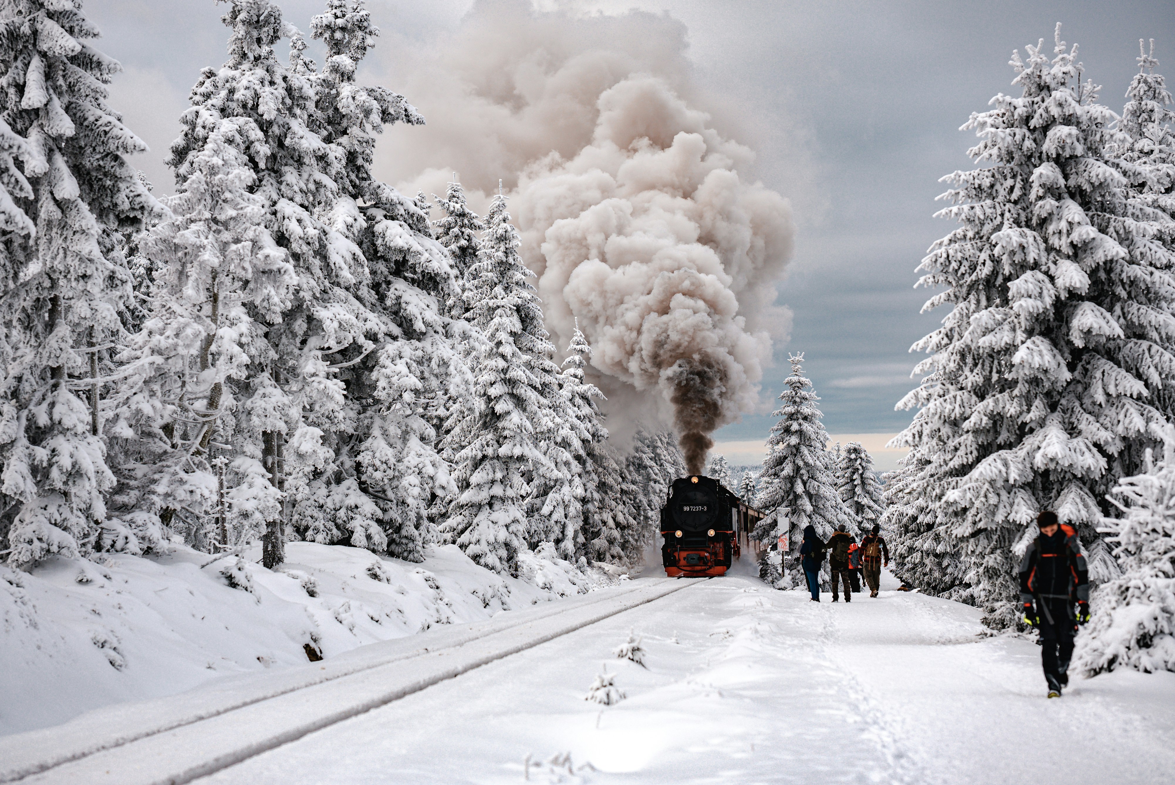 a train on a track with people walking on the side