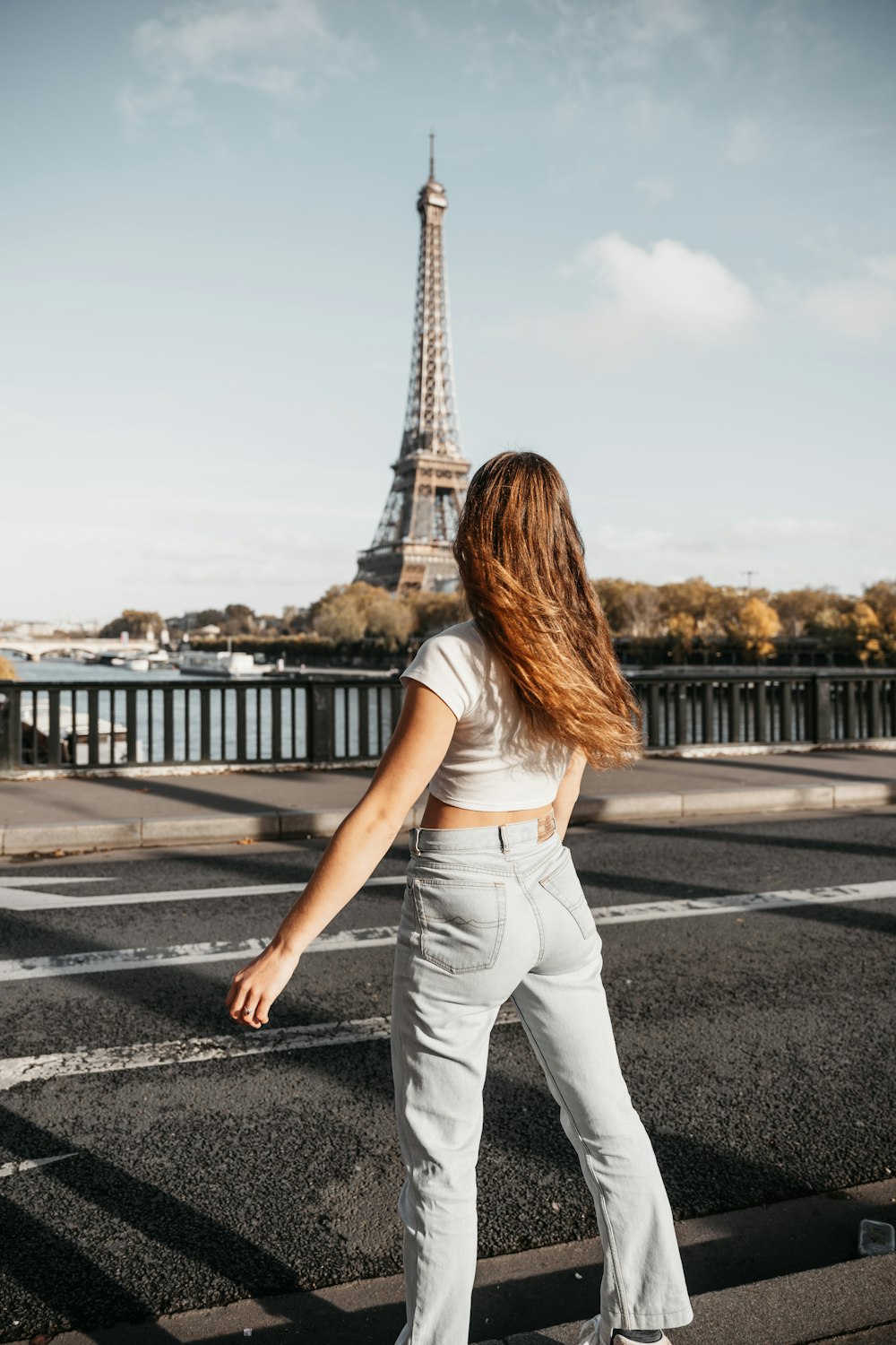 a woman standing on a bridge looking at the eiffel tower
