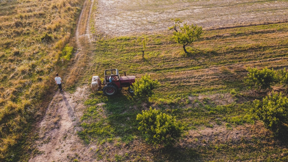 eine Person, die neben einem Traktor auf einem Feld steht